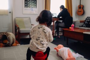 A parent works in the background as a child plays during work from home quarantine