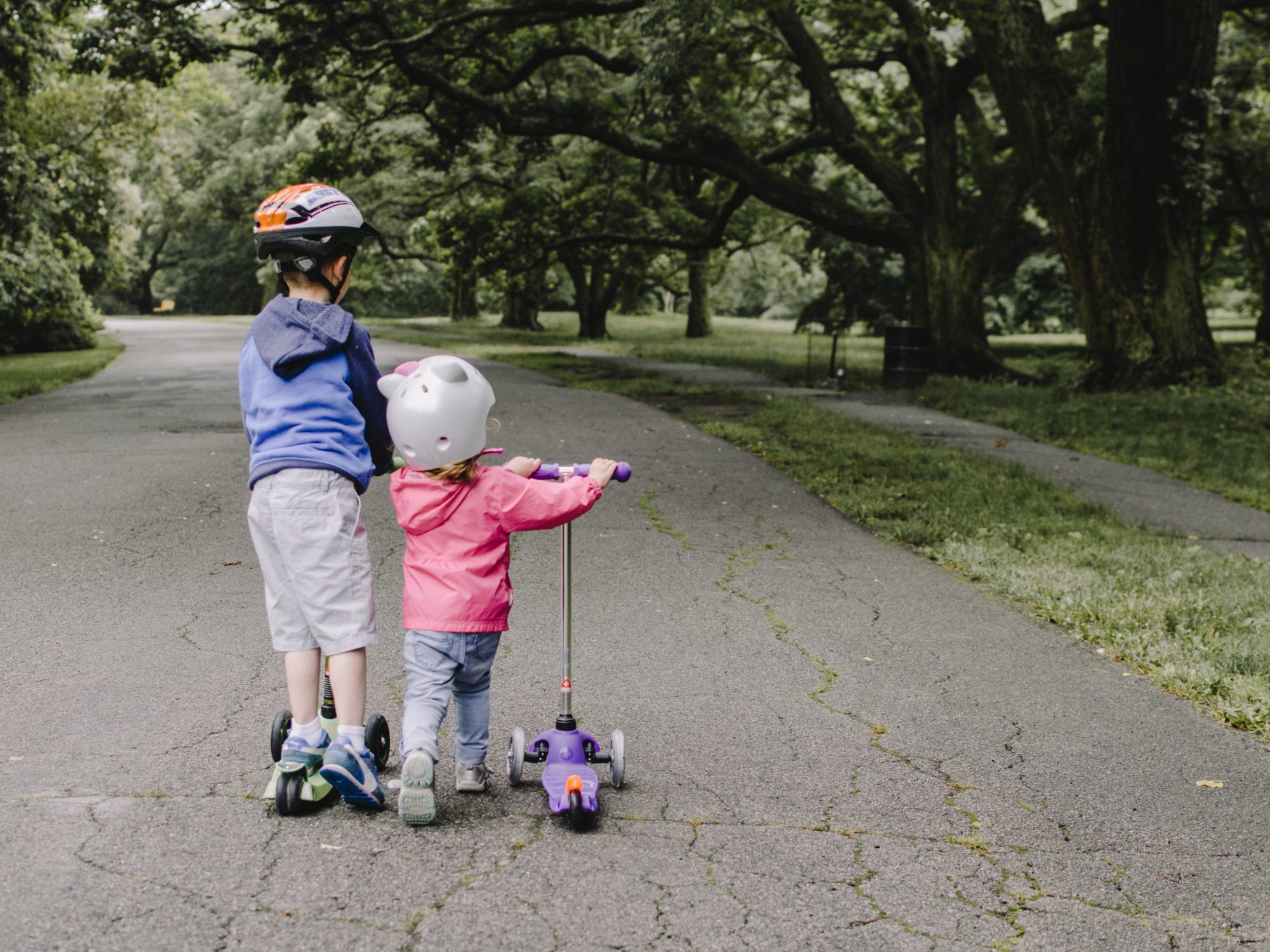 Children riding scooters wearing helmets for safety