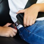 Child buckling his seat belt for summer safety