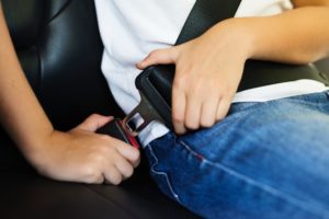 Child buckling his seat belt for summer safety